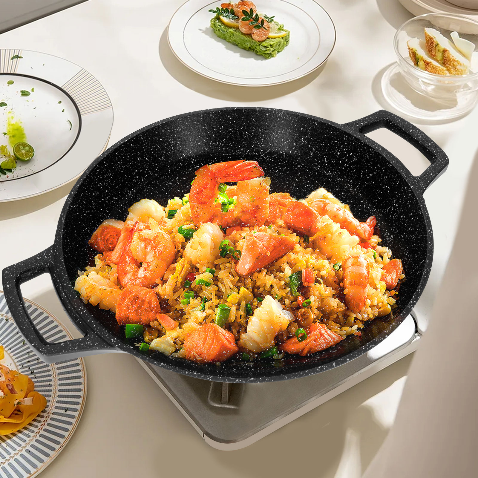 Un wok avec du riz frit aux crevettes. D'autres assiettes avec de la nourriture sont sur la table blanche.