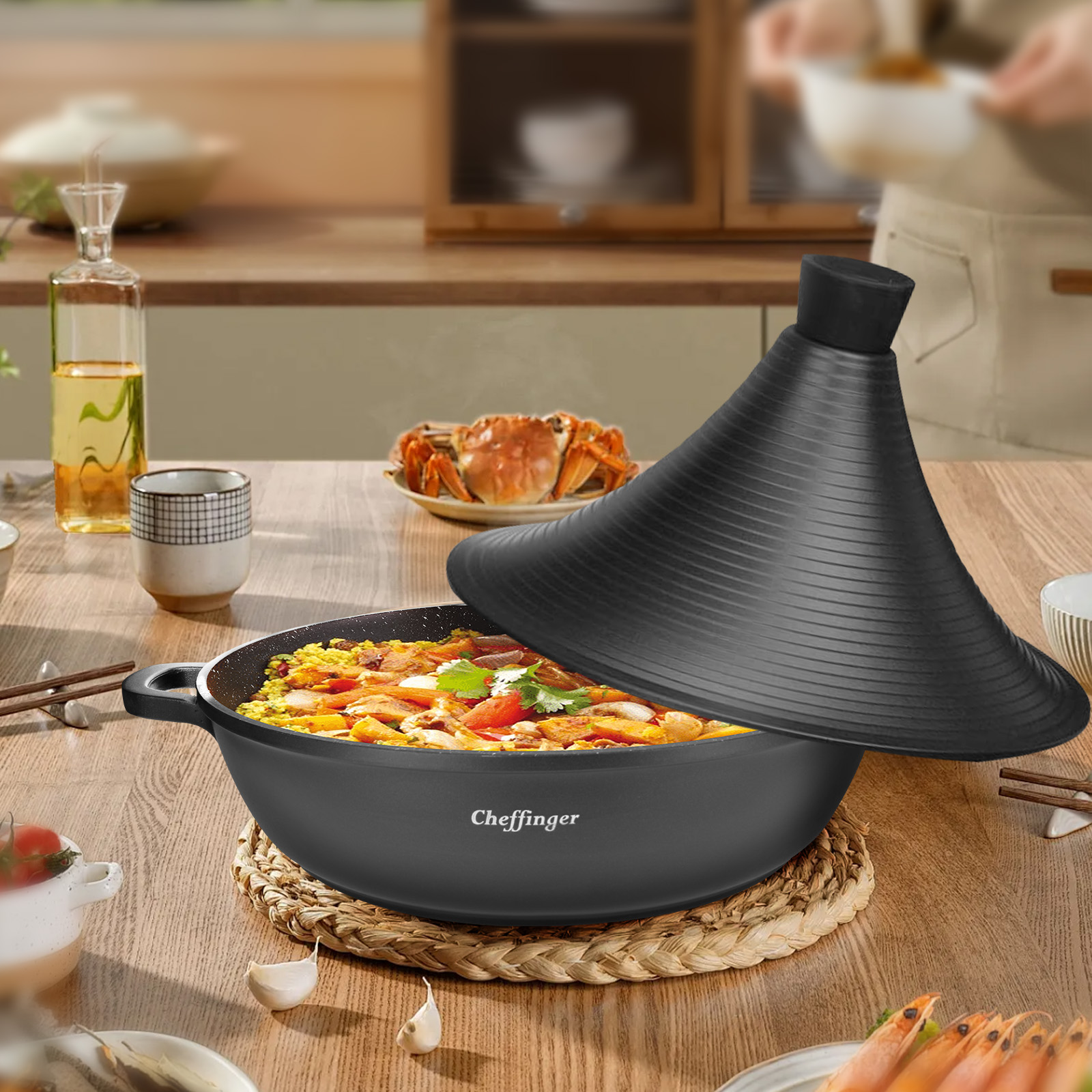 Una olla de tagine negra con la tapa abierta, llena de comida. Cangrejo y camarones sobre la mesa de madera.