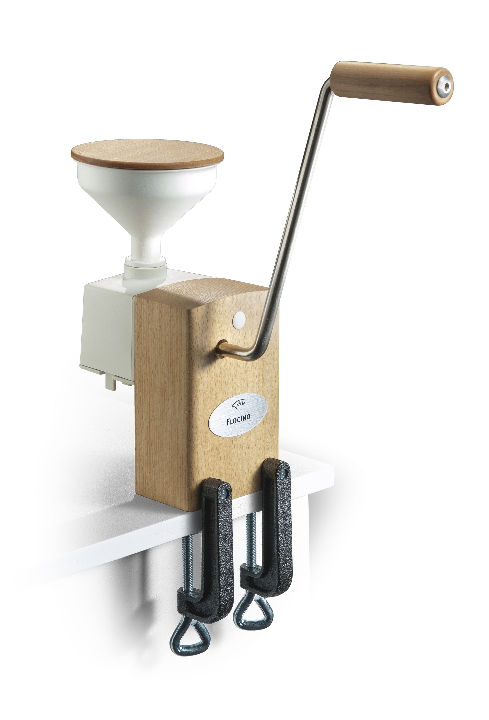 Eine manuelle Getreidemühle. Sie hat einen Holzkörper, einen weißen Trichter und einen Griff. Sie ist an einer weißen Oberfläche befestigt.