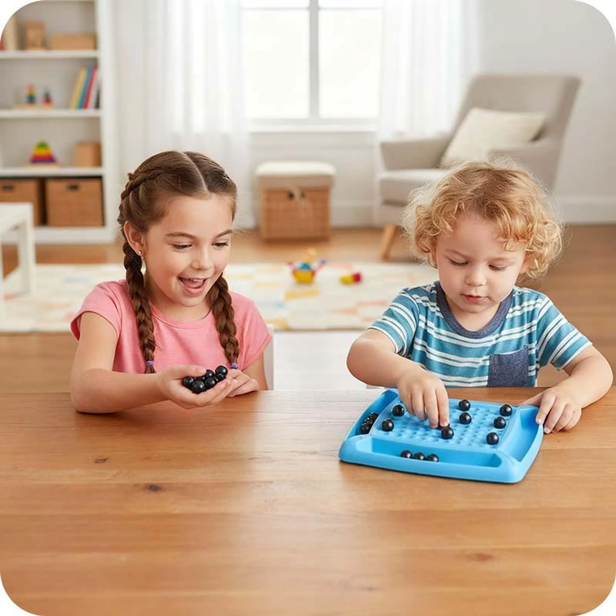 Zwei Kinder spielen ein Spiel mit schwarzen Murmeln. Das Mädchen hält Murmeln, der Junge legt sie in ein blaues Brettspiel.