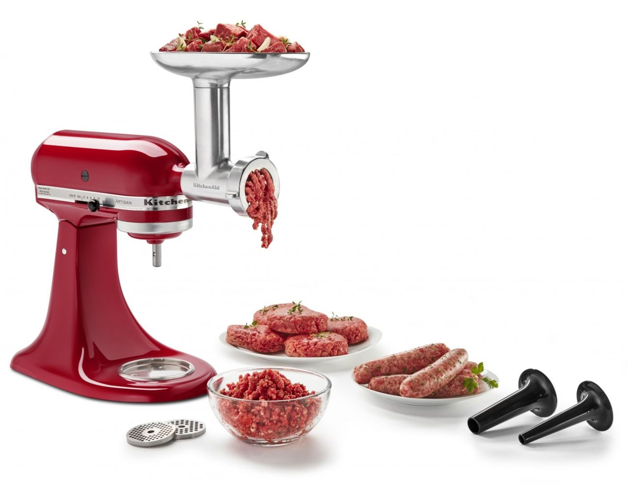 Ein roter KitchenAid-Fleischwolf verarbeitet Fleisch. Gehacktes, Buletten und Würste werden gezeigt. Zwei schwarze Wurstfüller befinden sich rechts.