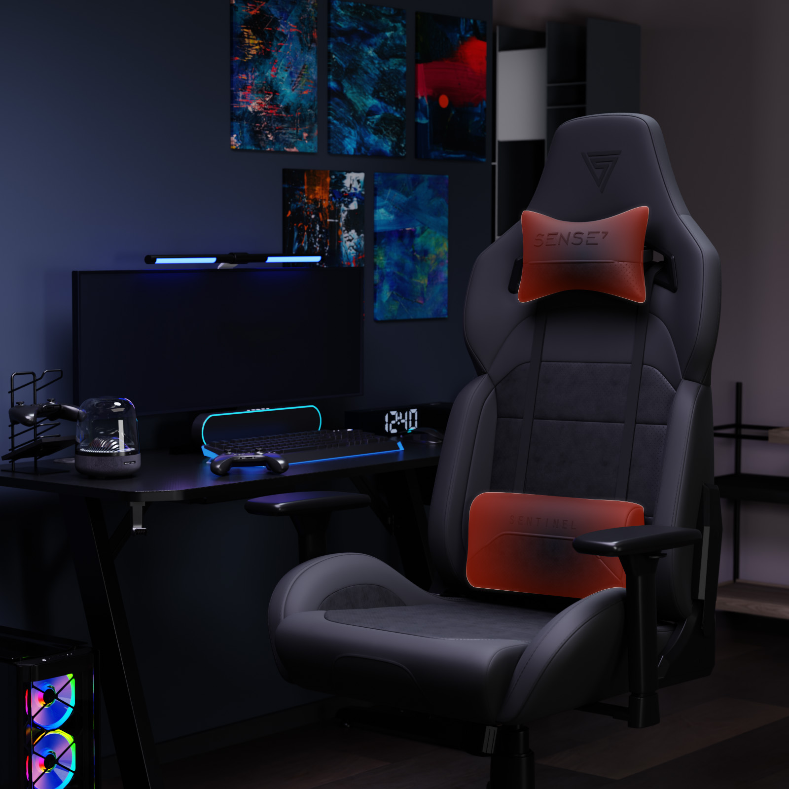Een gaming setup met een stoel, bureau, monitor en kunstwerken. Stoel heeft rode kussens. Bureau heeft toetsenbord, luidspreker, controllers.