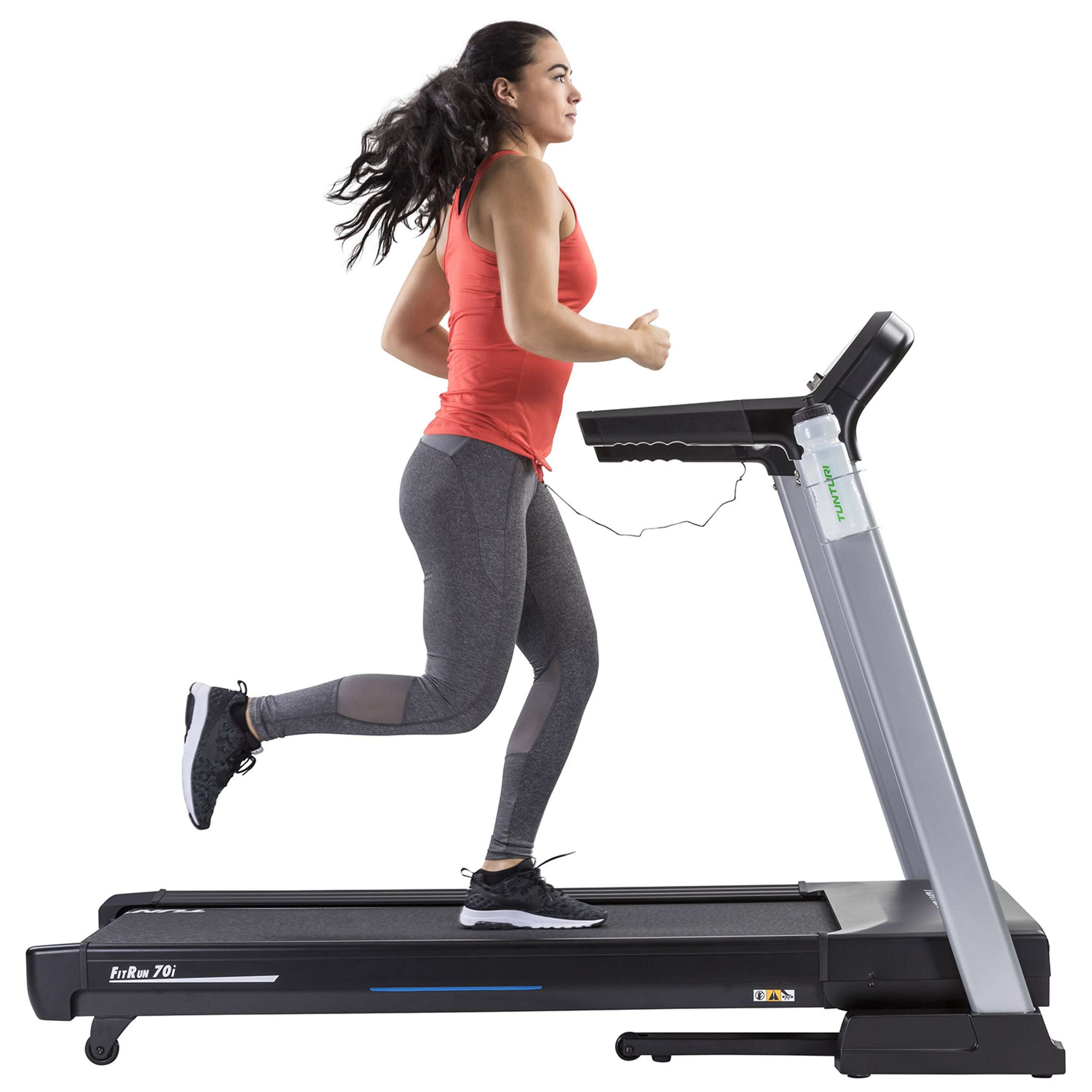 Een vrouw rent op een loopband. Ze draagt een rode top en grijze leggings. De loopband is zwart en zilver.