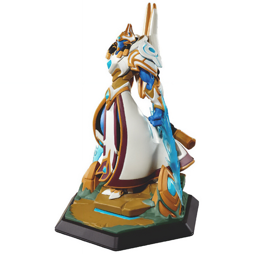 Statuetta di un personaggio in armatura bianca e oro con dettagli blu, in piedi su una base con una spada. La base è nera e oro.