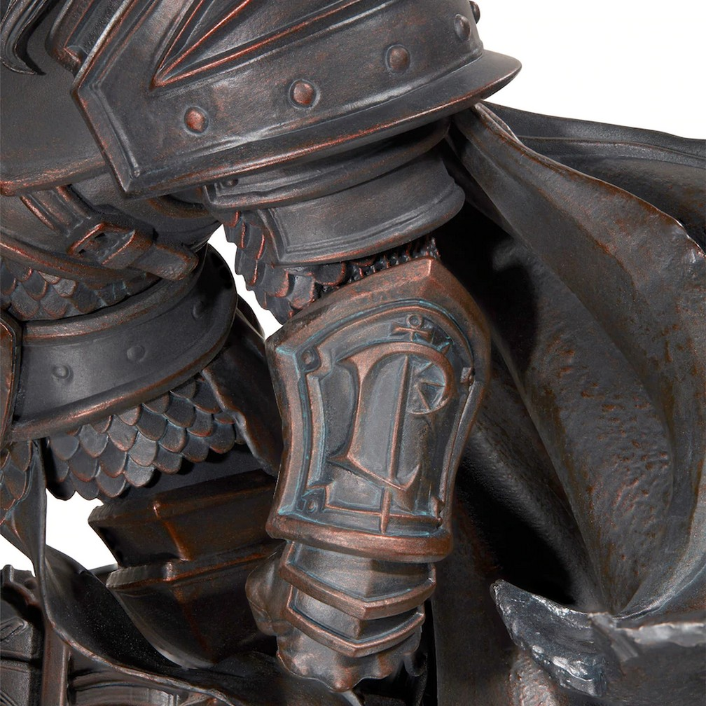 Primo piano di una statua raffigurante un cavaliere in armatura. L'armatura è di colore metallico scuro con accenti bronzo, un mantello è drappeggiato.