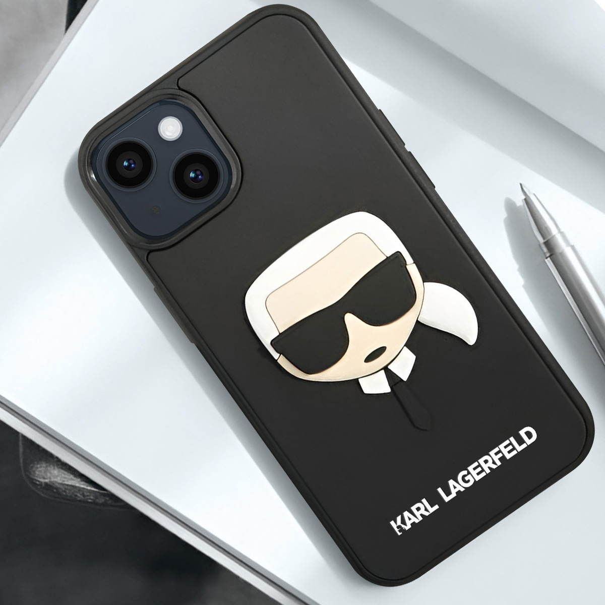 Telefono nero con design Karl Lagerfeld. Il telefono è su una superficie bianca con una penna.