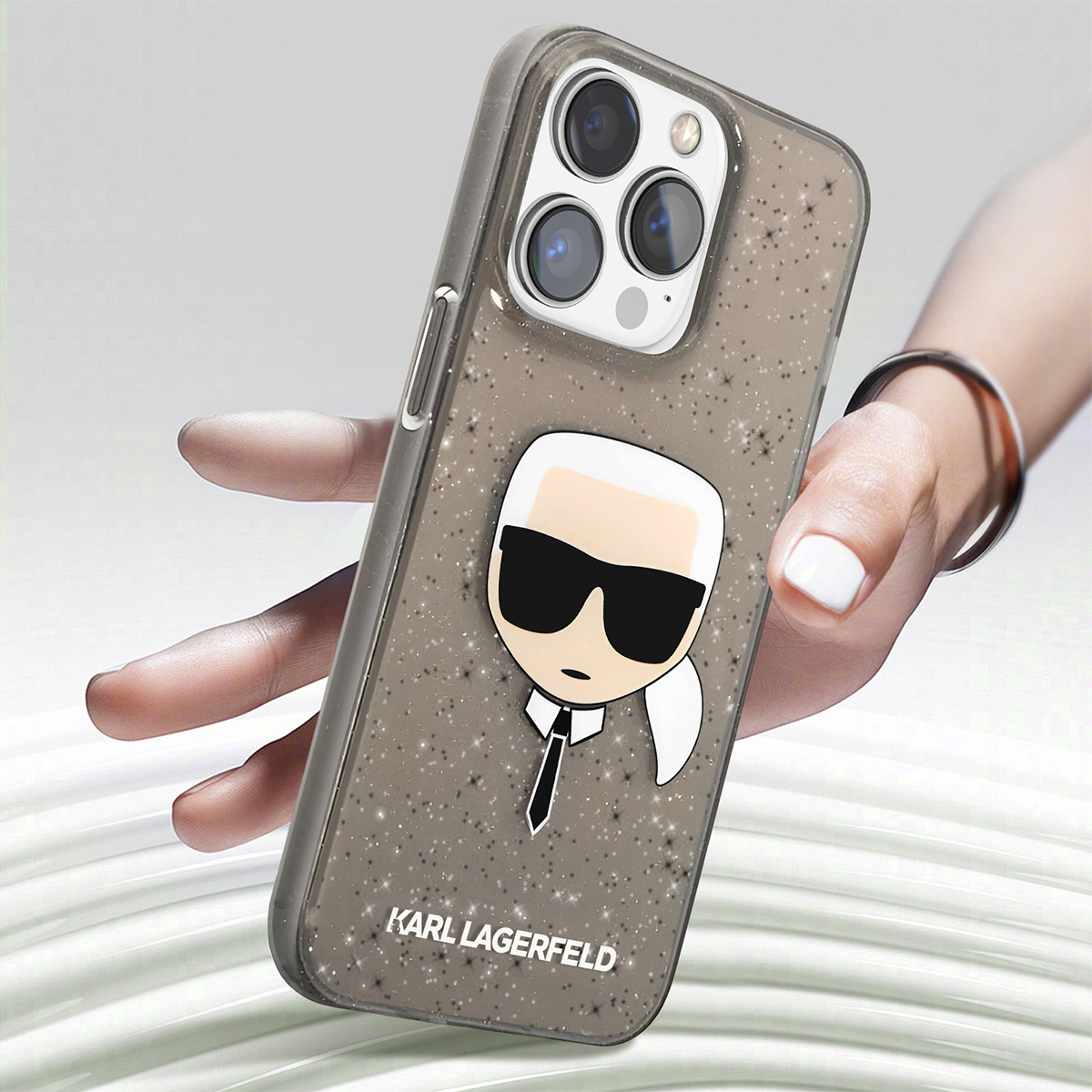 Una custodia per telefono con un design Karl Lagerfeld è tenuta in mano. La custodia ha un'immagine a cartoni animati e il logo del marchio.