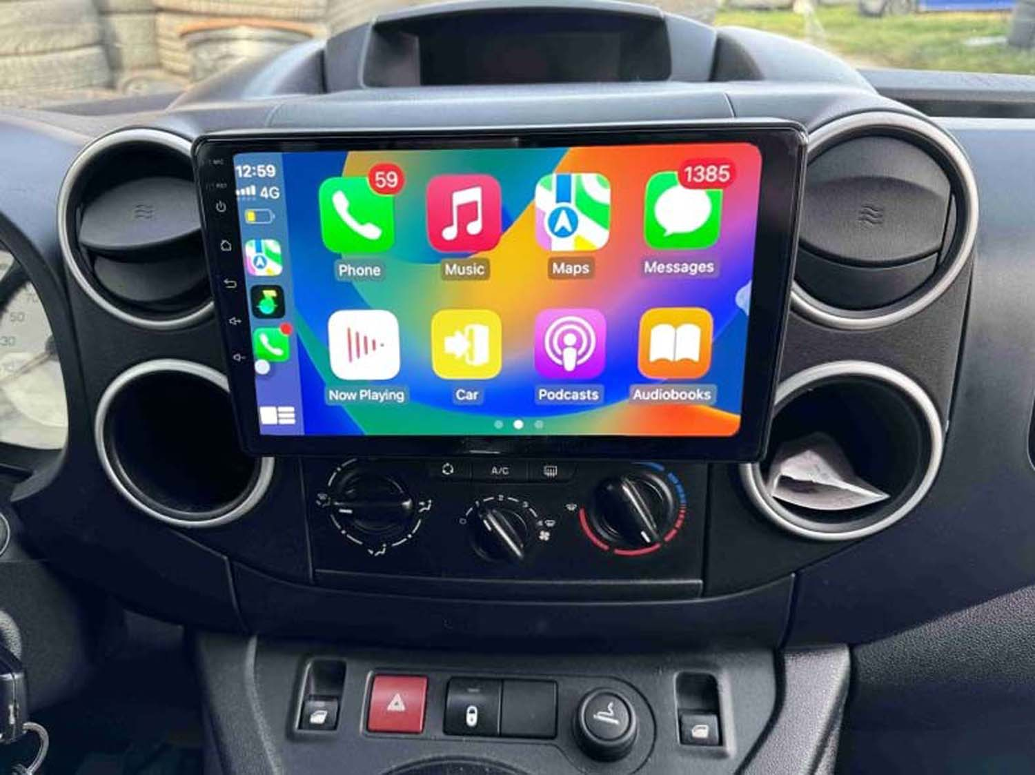 Cruscotto dell'auto con display touchscreen con icone delle app. Telefono, musica, mappe e messaggi sono visibili, insieme ai comandi dell'auto.