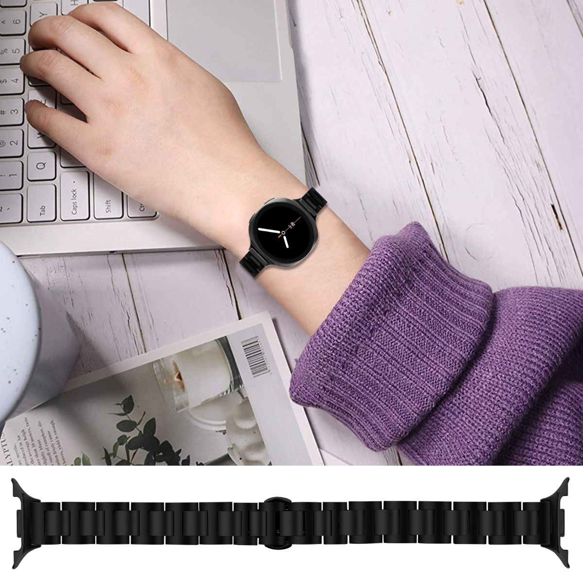 Il polso di una persona con un orologio nero è su una scrivania bianca. Sotto c'è un cinturino separato. Sono visibili anche un laptop e un maglione viola.
