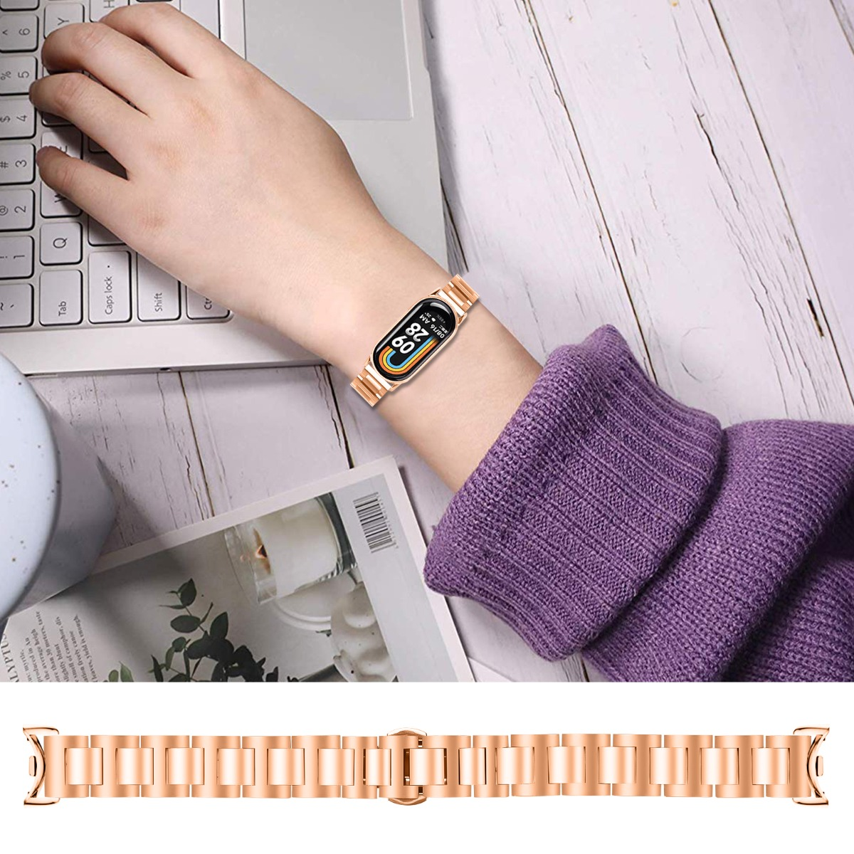 Una persona con un reloj inteligente oro rosa en la muñeca, tecleando en un portátil. La correa del reloj es detallada y una correa de repuesto está debajo.