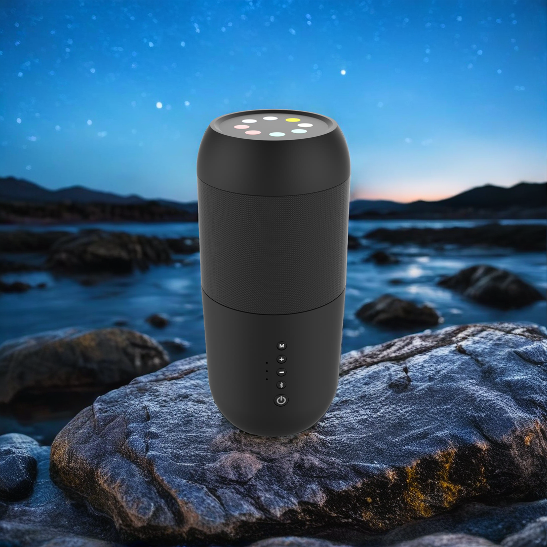 Un altavoz negro sobre una roca. Detrás, hay agua y un cielo nocturno con estrellas.