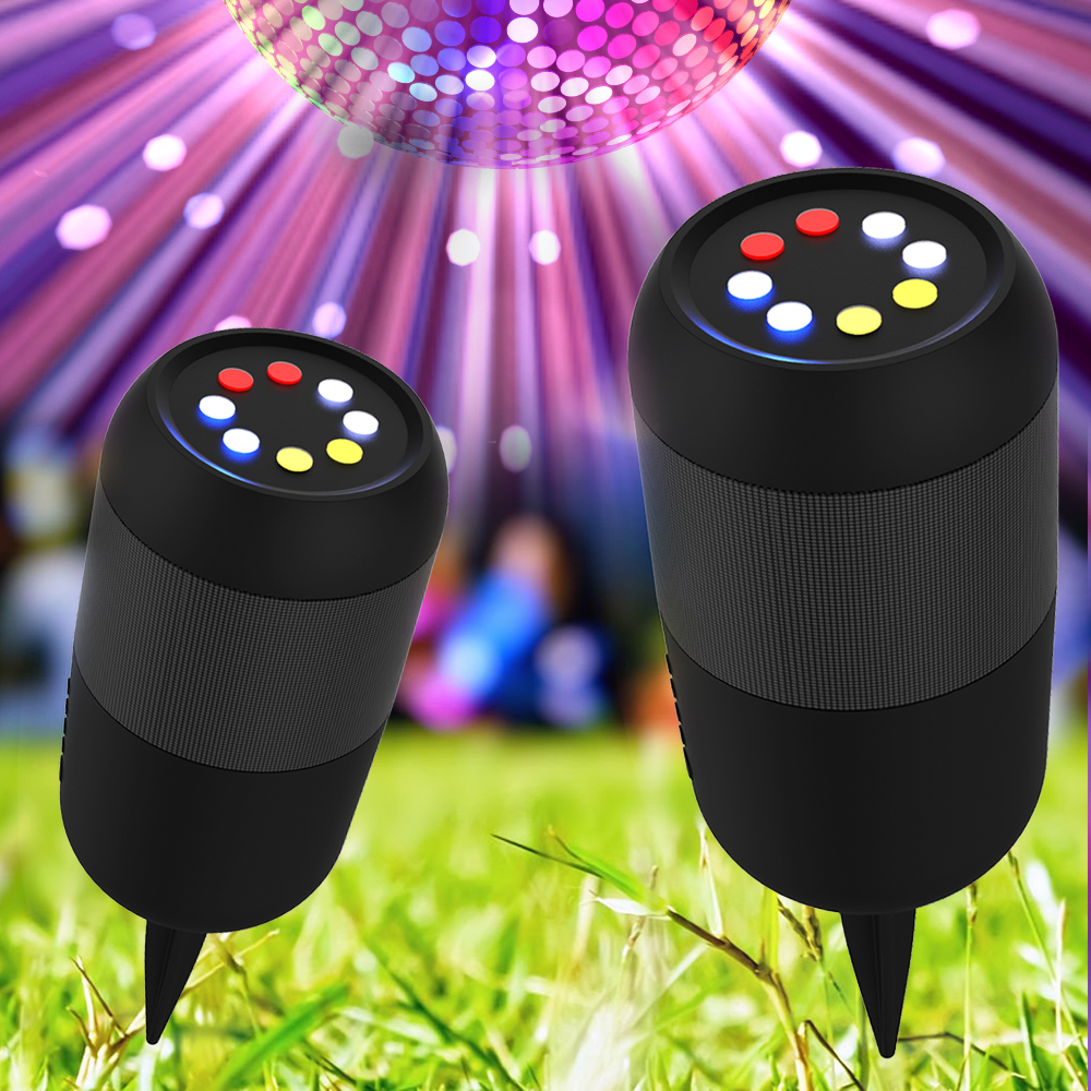 Dos altavoces negros con luces de colores arriba, en hierba verde con una bola de discoteca y fondo colorido.