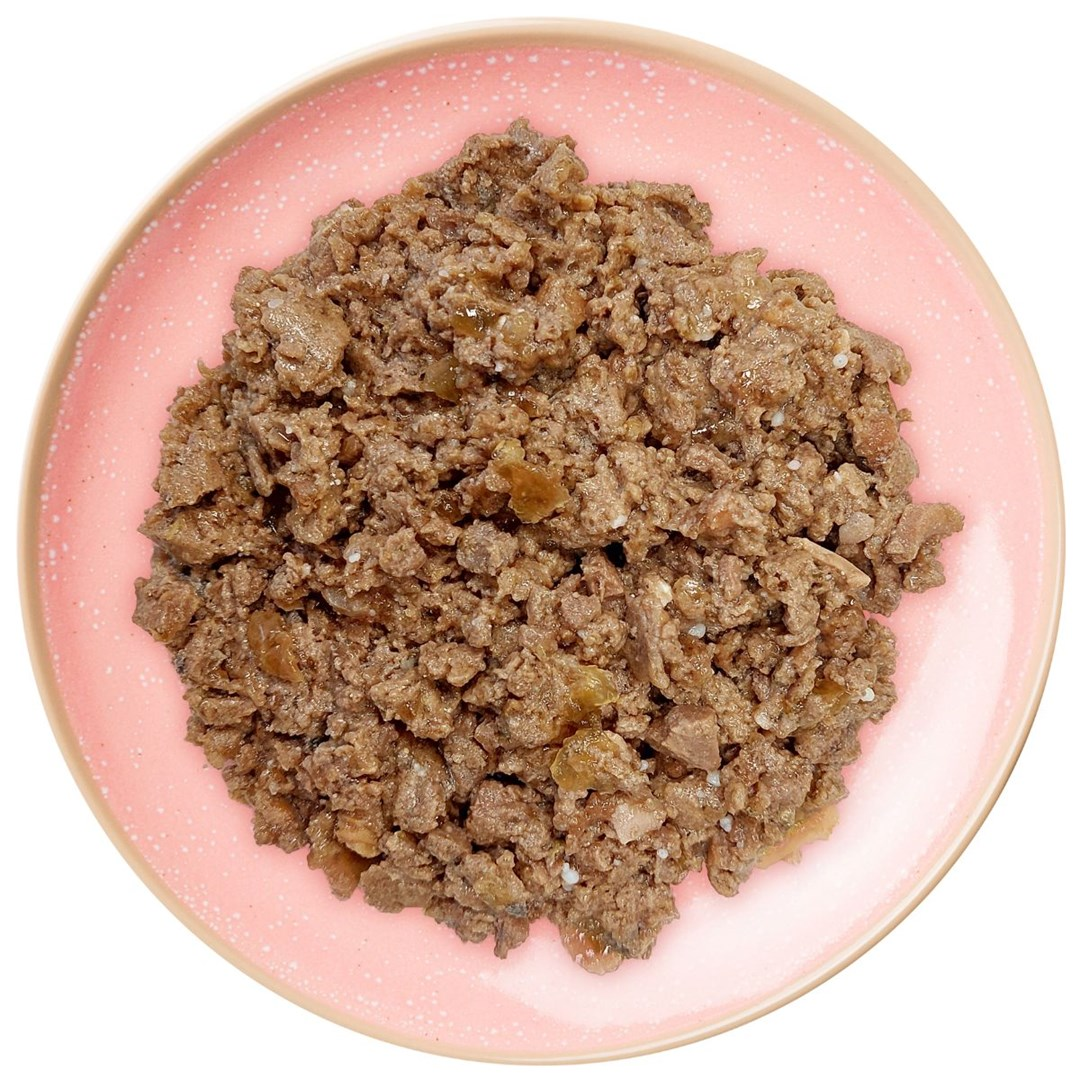 Brązowe, teksturowane jedzenie na różowym talerzu. Talerz ma nakrapiany wzór. Jedzenie wydaje się mokre z widocznymi kawałkami.