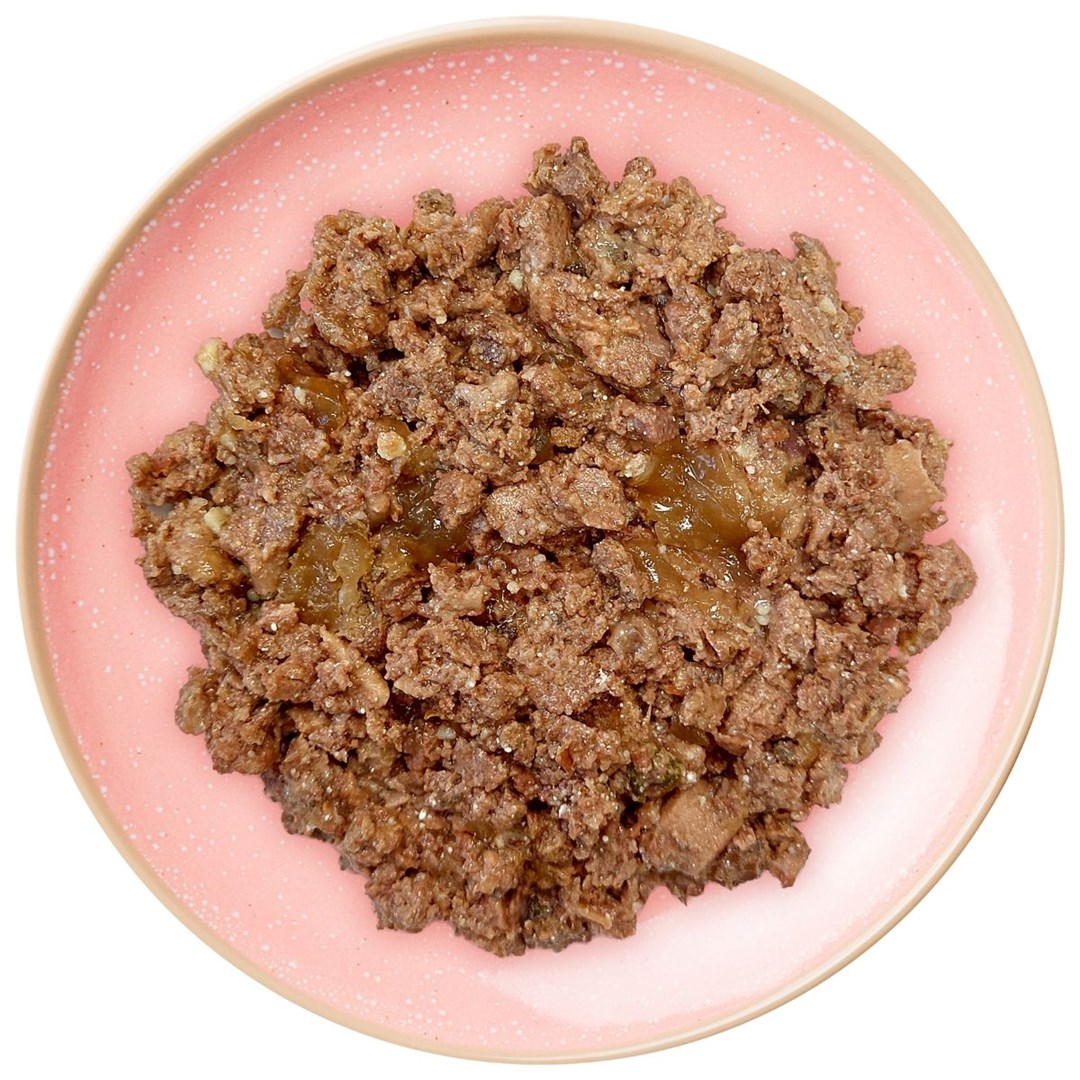 Różowy talerz z brązowym, mielonym jedzeniem. Jedzenie wydaje się być mięsem z przezroczystą, galaretowatą substancją na wierzchu.