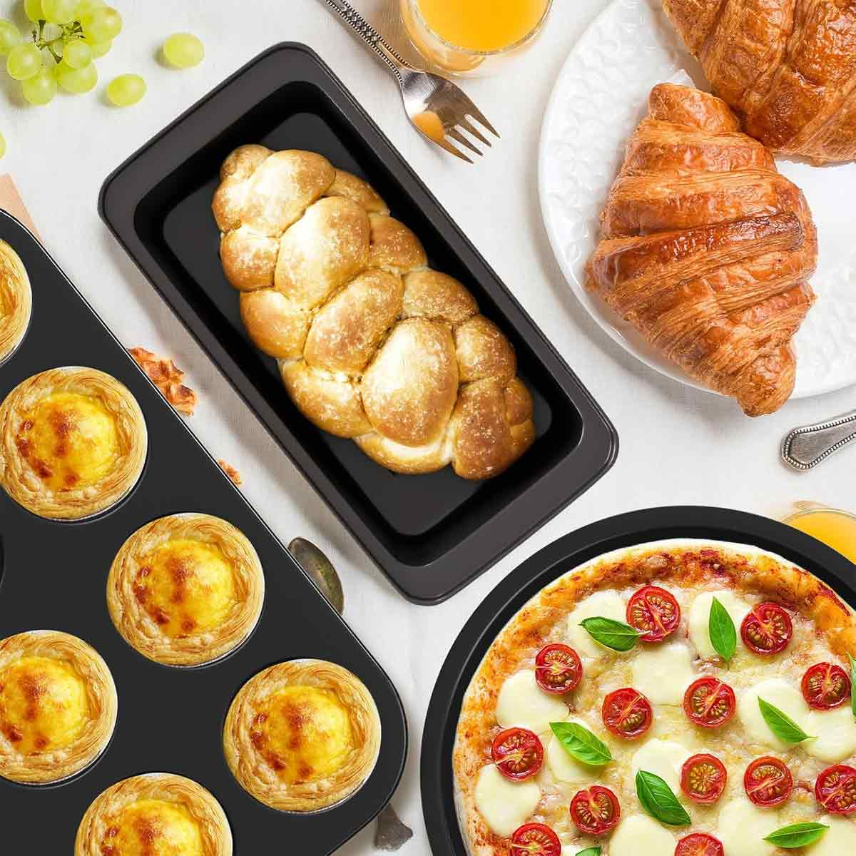 Draufsicht auf verschiedene Lebensmittel: Brot in einer Pfanne, Croissants, Pizza und Eiertörtchen. Trauben und Saft sind ebenfalls sichtbar.