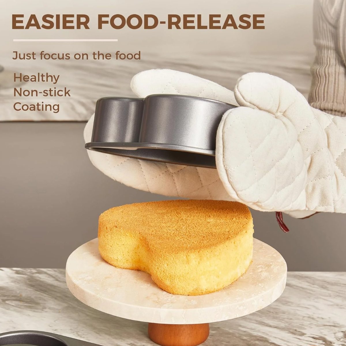 Ein herzförmiger Kuchen auf einem Ständer. Eine Person hält eine Backform. Der Text lautet 'Easier Food-Release'.