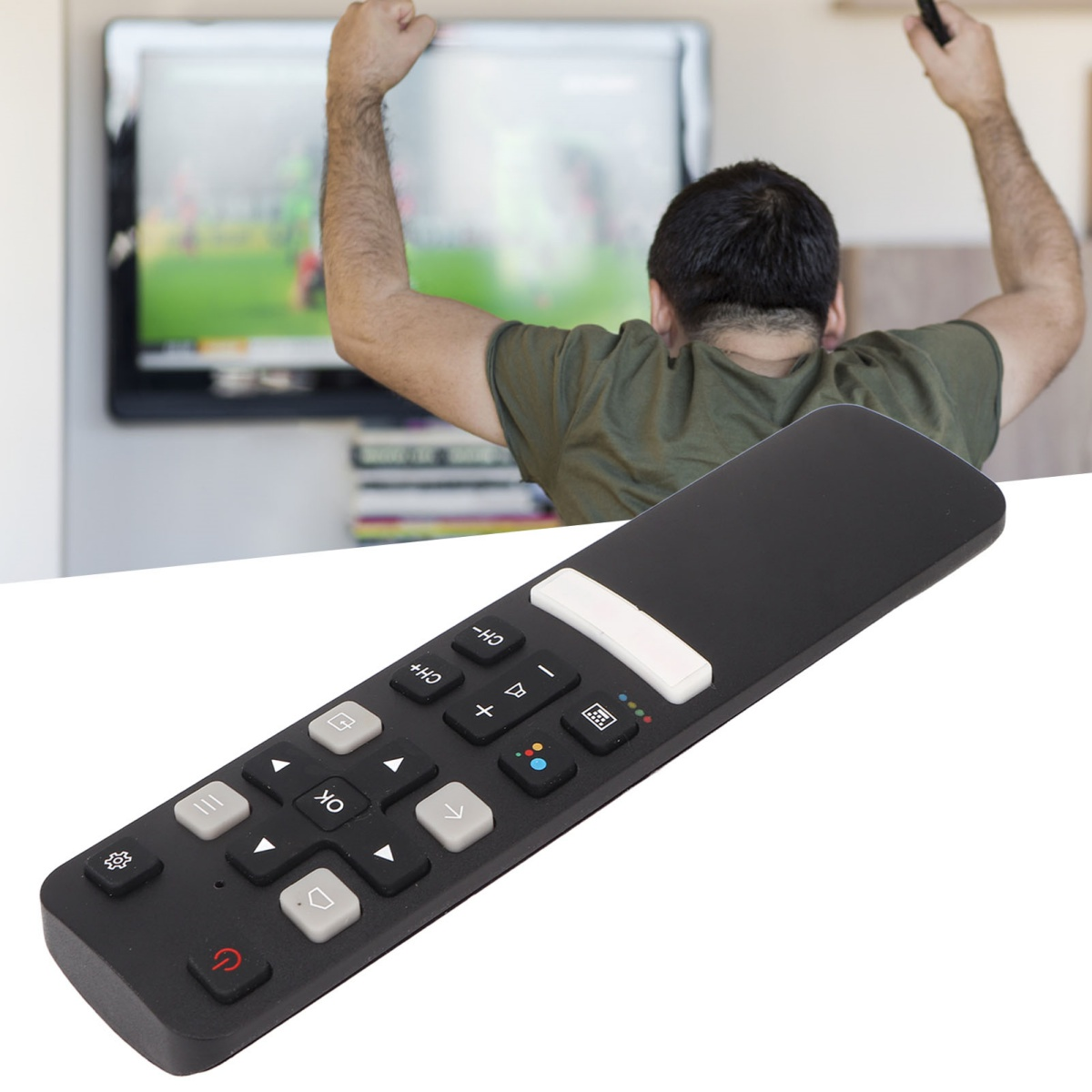 Ein Mann jubelt vor einem Fernseher und hält eine Fernbedienung. Der Fernseher zeigt ein Fußballspiel. Eine schwarze Fernbedienung steht im Fokus.