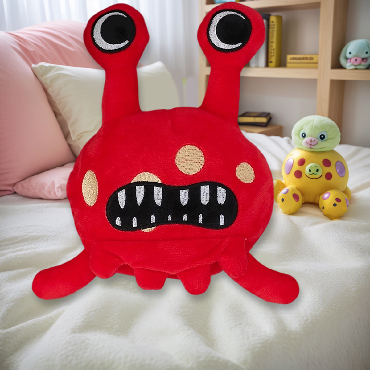 Rotes Plüschmonster mit großen Augen und Zähnen, liegt auf einem Bett. Es gibt ein weiteres gelbes Monst Spielzeug mit einem grünen Kopf.