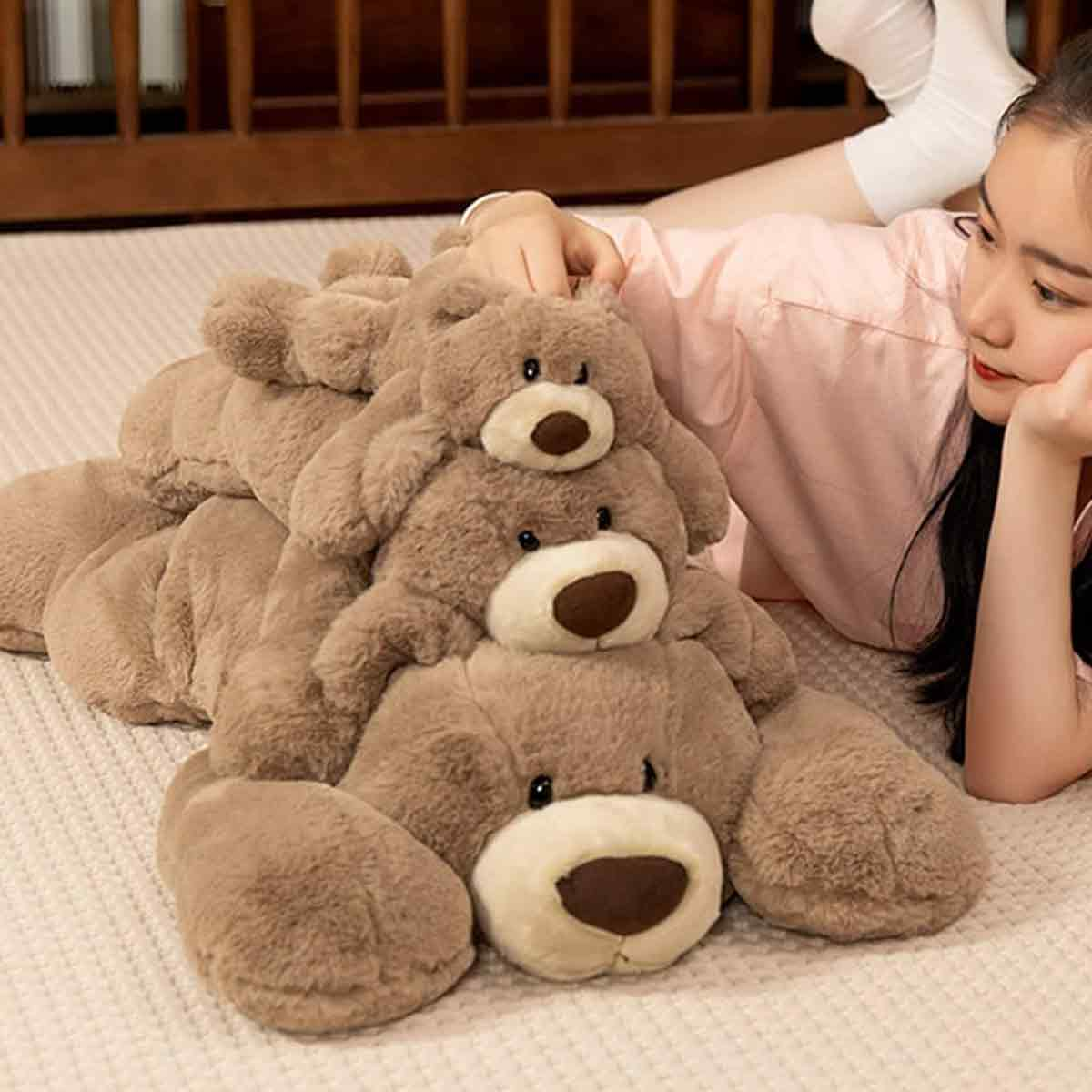 Eine Frau liegt mit drei Teddybären. Die Bären sind gestapelt, und die Hand der Frau ruht darauf.
