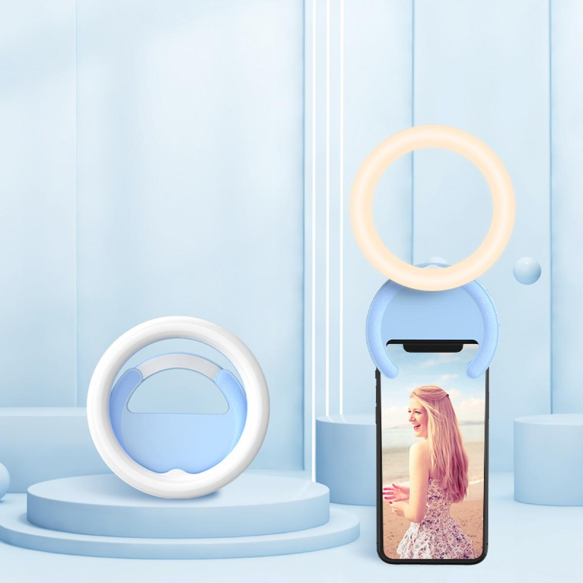 Ein Telefon mit einem Selfie-Lichtring. Das Telefon zeigt ein Foto einer Frau. Der Ring ist weiß und blau. Der Hintergrund ist hellblau.