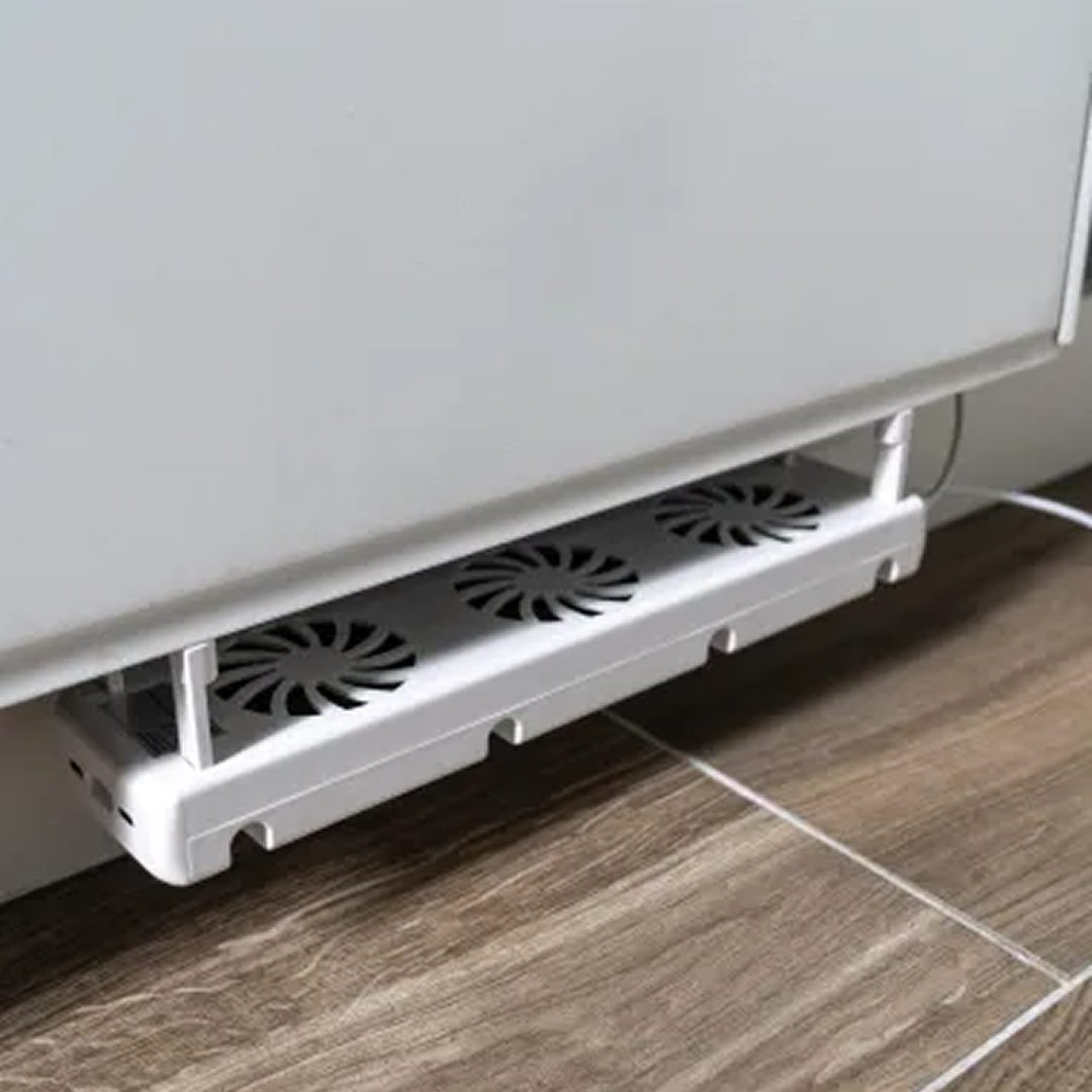 Een witte koelventilatoreenheid met drie ventilatoren is onder een wit apparaat gemonteerd. De eenheid staat op een houten vloer.