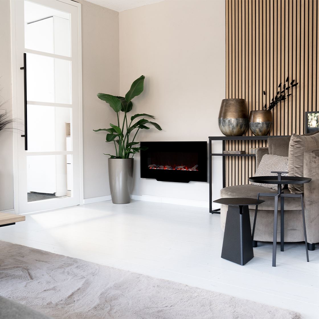 Living room scene with fireplace, plant, and sofa. Wooden paneling on the wall. Two vases on a shelf. White door, white floor.