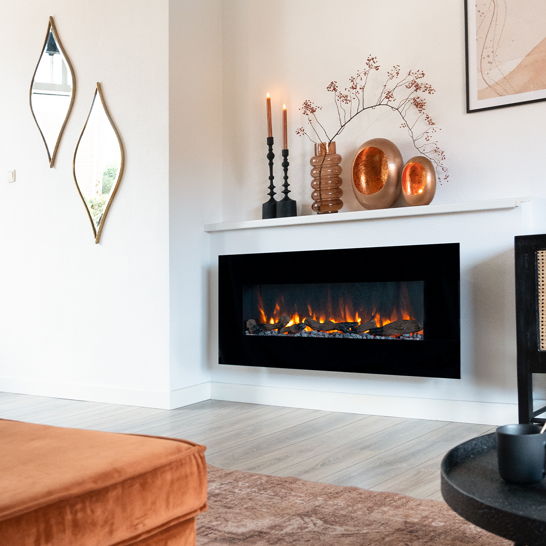 Moderne woonkamer met zwarte open haard, decoratieve items en een bank. Spiegels aan de muur, kaarsen branden.