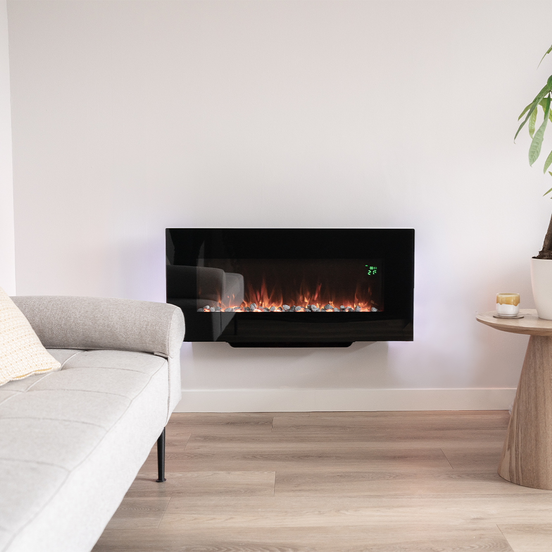 A modern living room with a black fireplace on the wall, a gray sofa, and a small wooden side table with a plant.