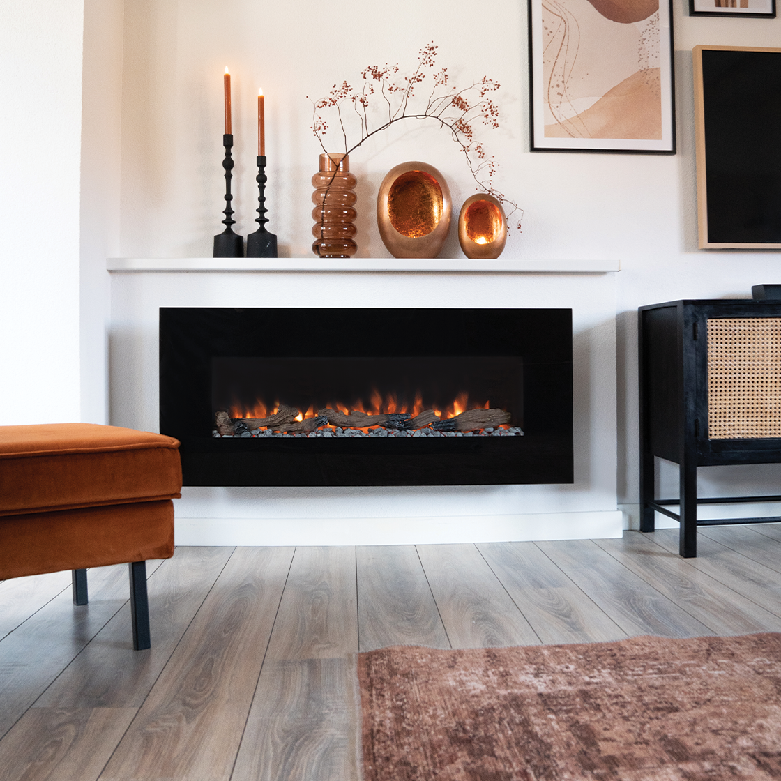 Een moderne woonkamer met een open haard, kaarsen en decoratieve items. De kamer heeft houten vloeren en een vloerkleed.