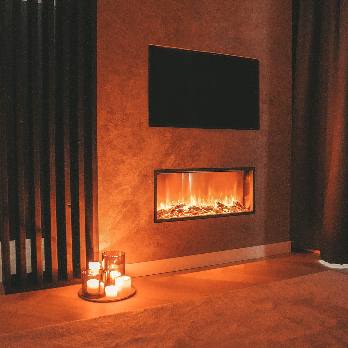 Een moderne kamer met een open haard, tv en kaarsen. De open haard heeft een vlameffect. Kaarsen branden op een dienblad.