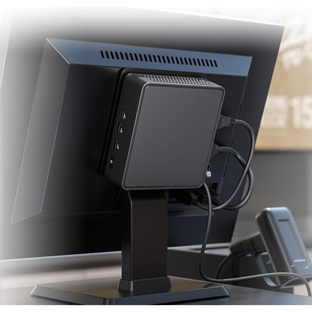 Czarny komputer jest zamontowany na monitorze. Kable są podłączone do komputera. Czarny stojak trzyma monitor.