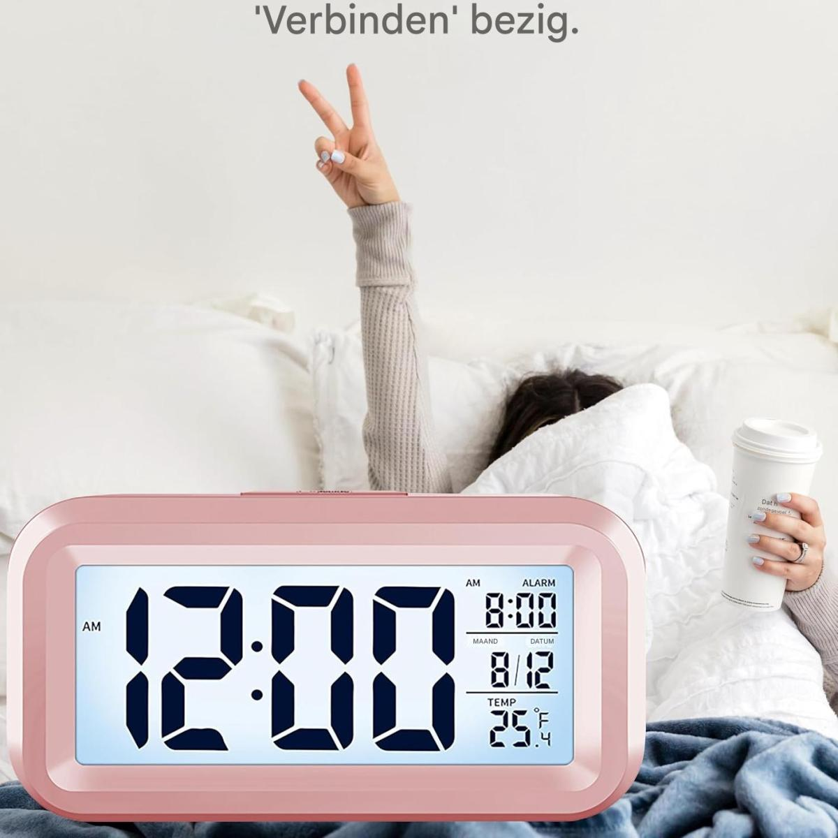 Una persona a letto con una sveglia che mostra le 12:00. La persona tiene in mano una tazza di caffè e fa il segno della pace.