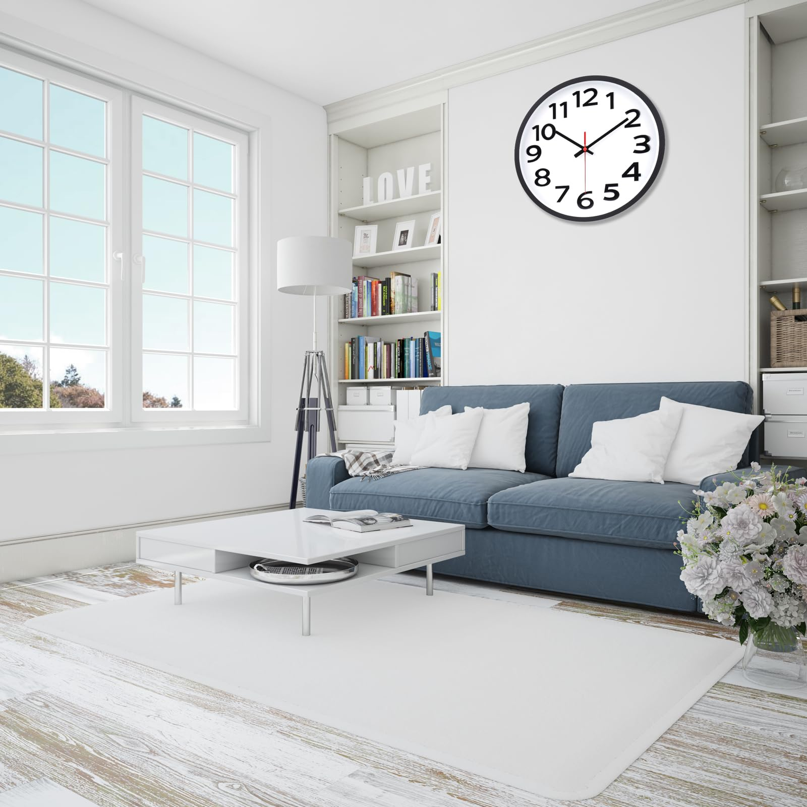 Wohnzimmer: blaues Sofa, weißer Teppich, Couchtisch, großes Fenster, Uhr an der Wand, Bücherregal.