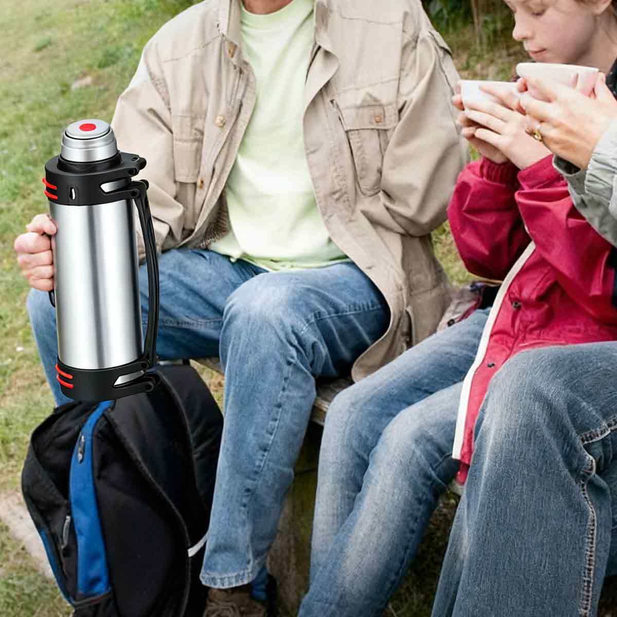 Eine Person hält eine silberne Thermoskanne. Andere trinken aus Tassen. Ein Rucksack steht unten. Menschen tragen Jacken und Jeans, sitzen draußen.