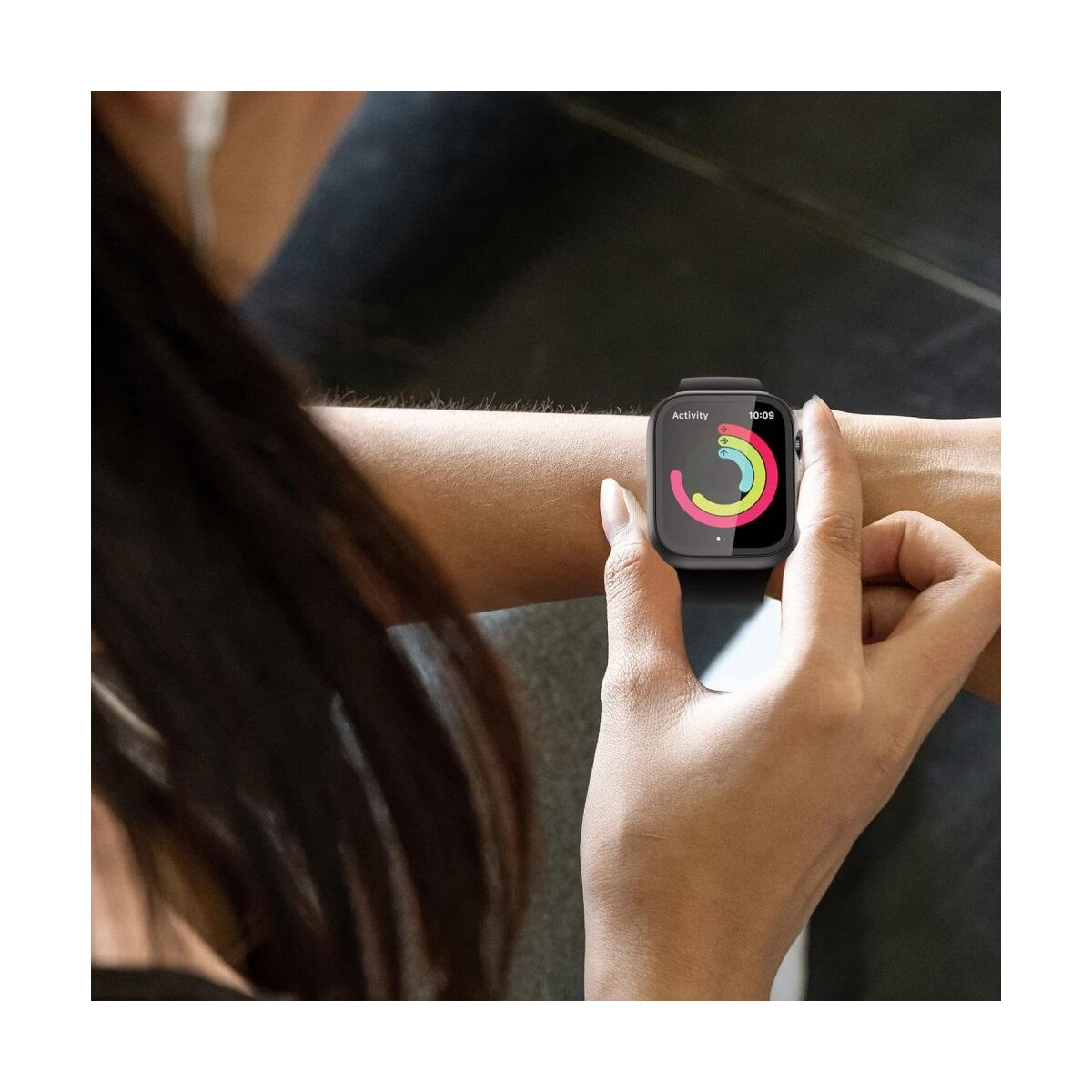 Une personne porte une smartwatch affichant des anneaux d'activité. La montre est au poignet, avec des cheveux foncés au premier plan.