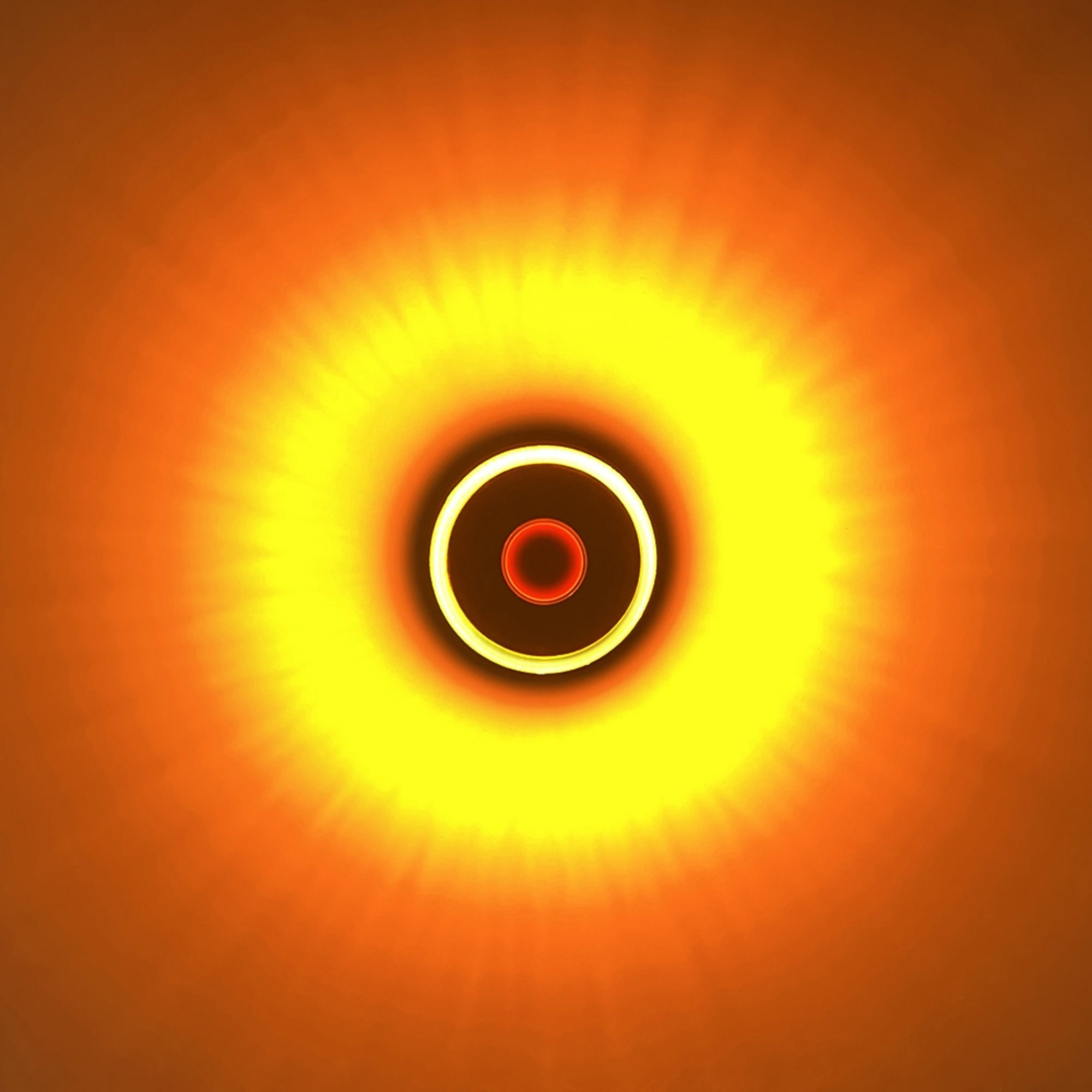 Imagen abstracta con un punto rojo central rodeado de círculos concéntricos amarillos y naranjas.