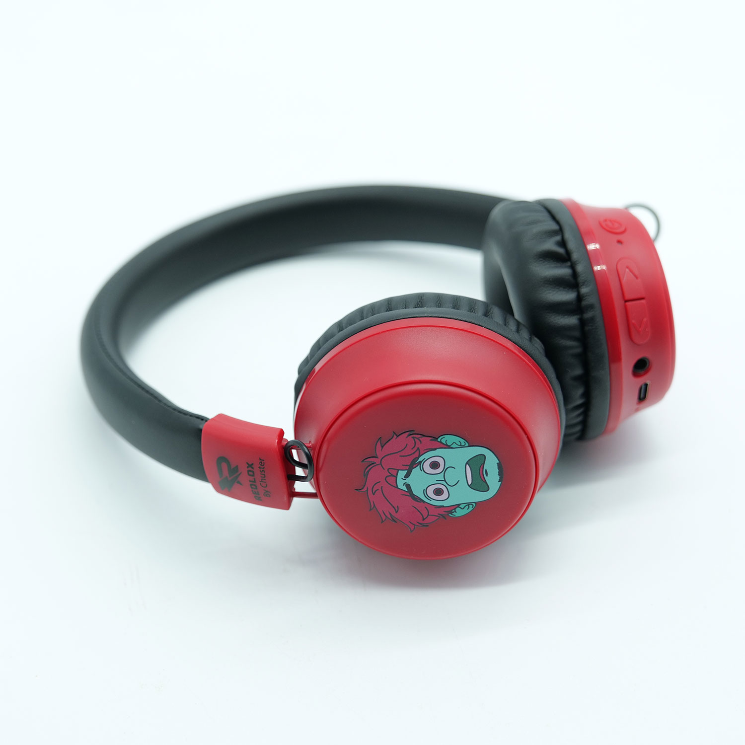 Cuffie rosse e nere con un volto di cartone sul padiglione auricolare, su una superficie bianca.
