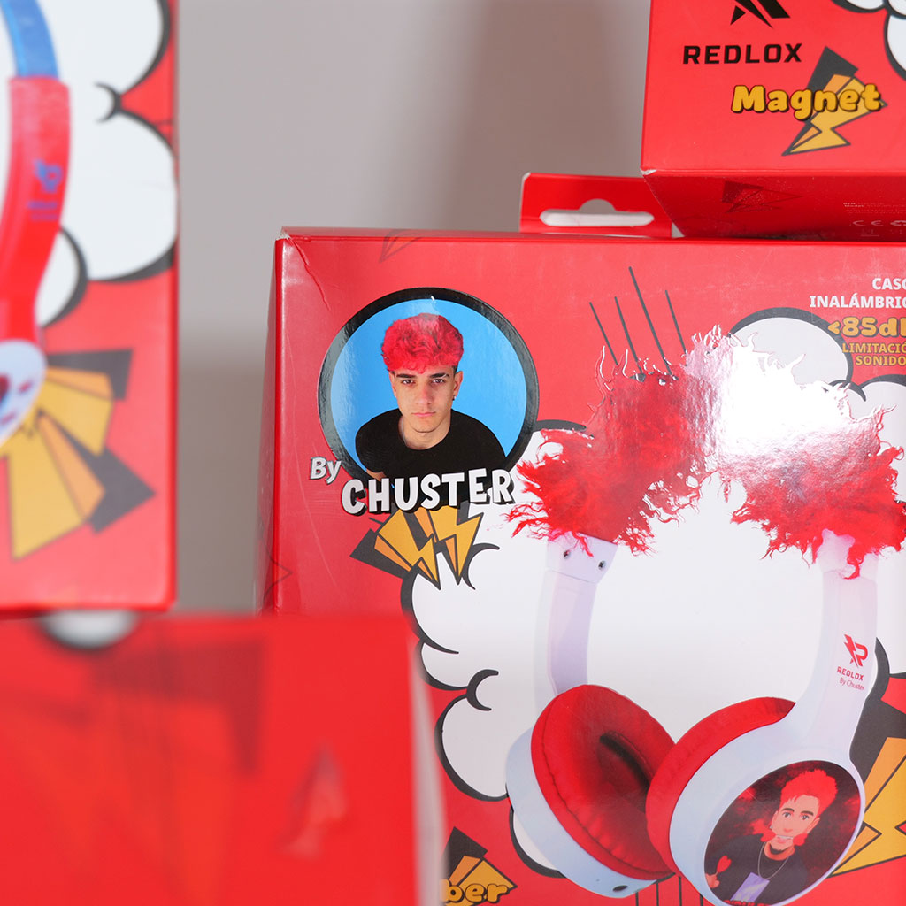Cuffie rosse in una scatola con l'immagine di un uomo con i capelli rossi. La scatola è rossa con dettagli bianchi.