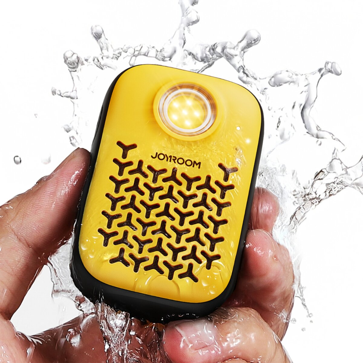 Ein gelber JOYROOM-Lautsprecher, der von einer Hand gehalten wird, mit Wasser, das um ihn herum spritzt. Der Lautsprecher hat einen schwarzen Rand und ein Licht.