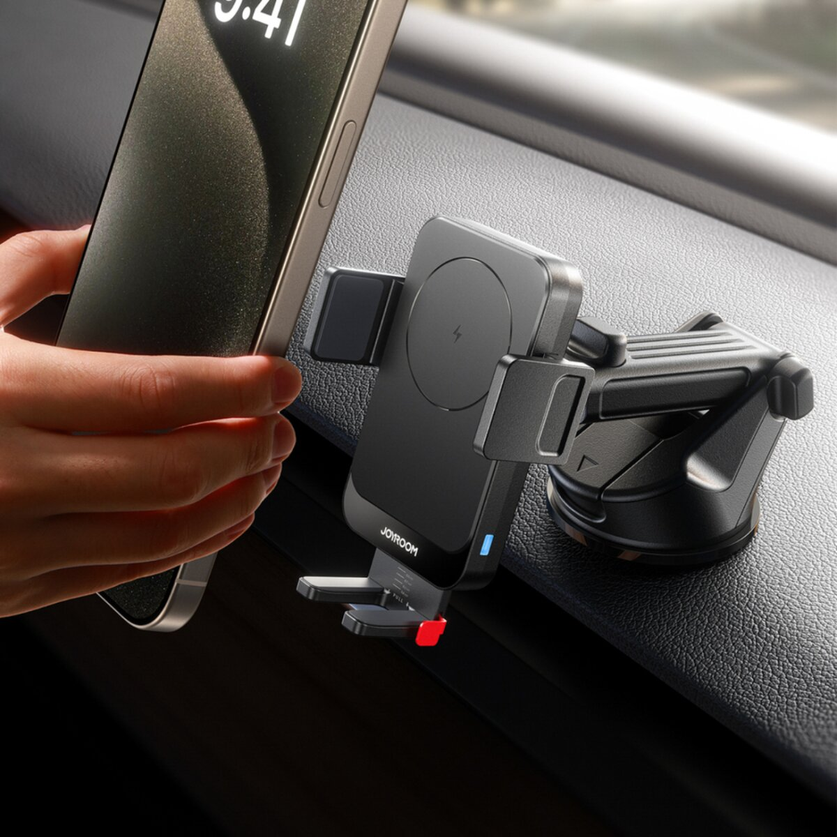 Eine Hand hält ein Telefon in der Nähe einer schwarzen Telefonhalterung in einem Auto. Das Telefon zeigt die Uhrzeit 9:41 an.