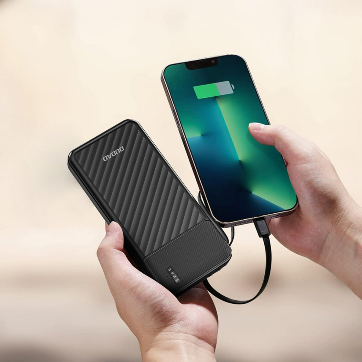 Un telefono si sta caricando con un power bank. Il telefono è verde e nero. Il power bank è nero. Entrambi sono tenuti da mani.
