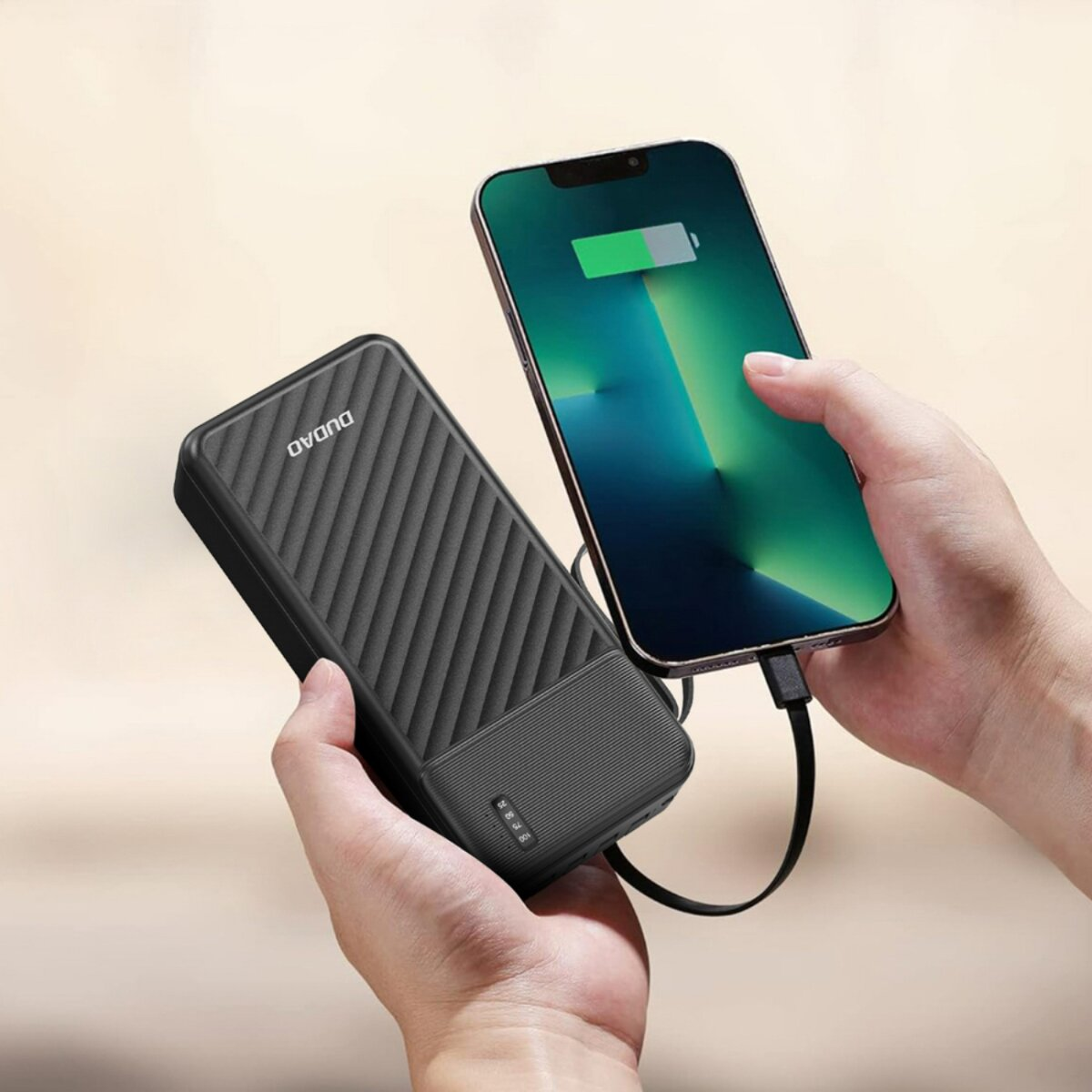 Un telefono si sta caricando da un power bank nero tenuto in mano. Lo schermo del telefono mostra un'icona di ricarica.