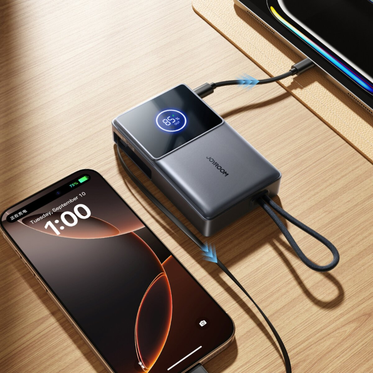 Un power bank carica due smartphone. Il power bank ha un display che mostra l'85%. Un telefono mostra il 75% di carica all'1:00 PM.