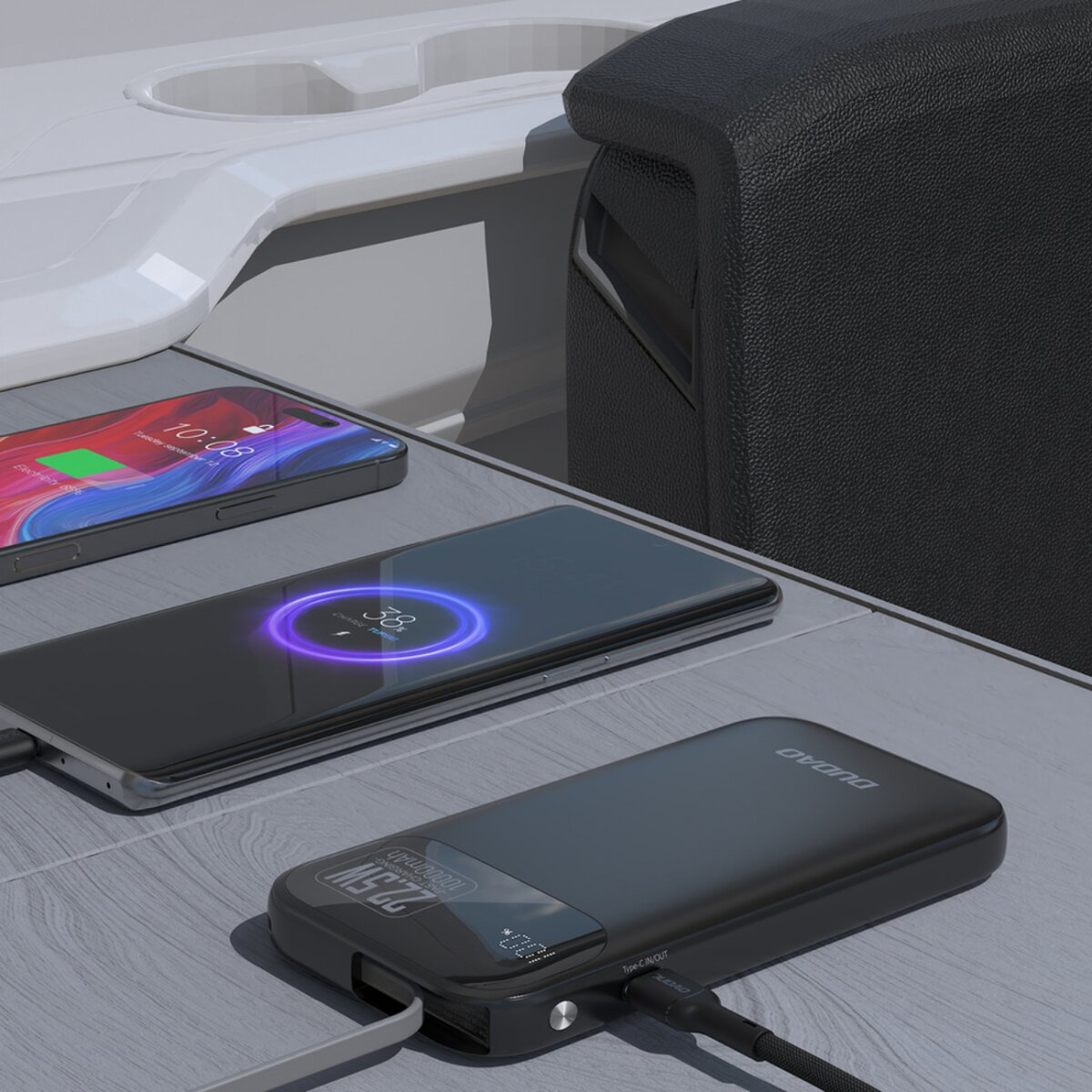 Un telefono in carica wireless, un altro telefono e un power bank in carica. Tutto su una superficie grigio chiaro, con l'interno di un'auto sullo sfondo.