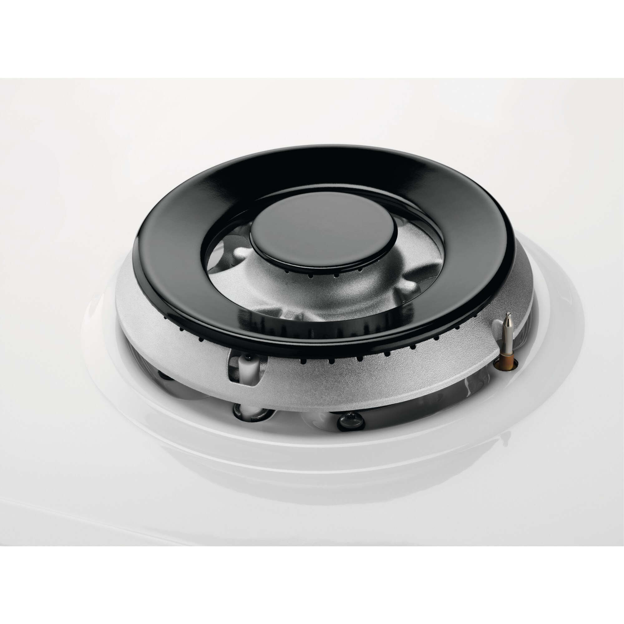 Primer plano de un quemador de cocina a gas. Tiene un anillo negro y un interior plateado, sobre una superficie blanca.