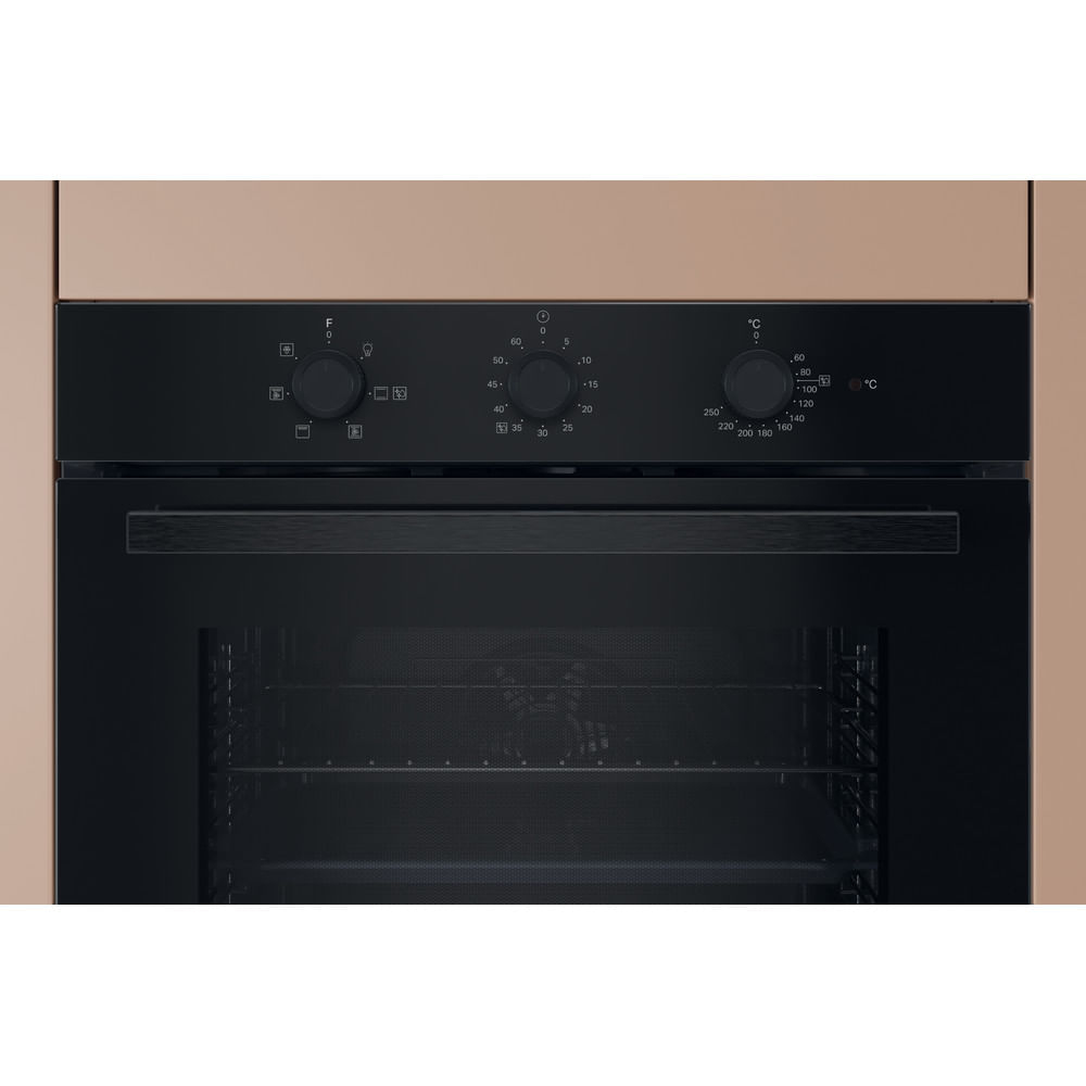 Primo piano di un forno a incasso. Ha comandi neri e una porta a vetri. Il forno è in un mobile marrone chiaro.