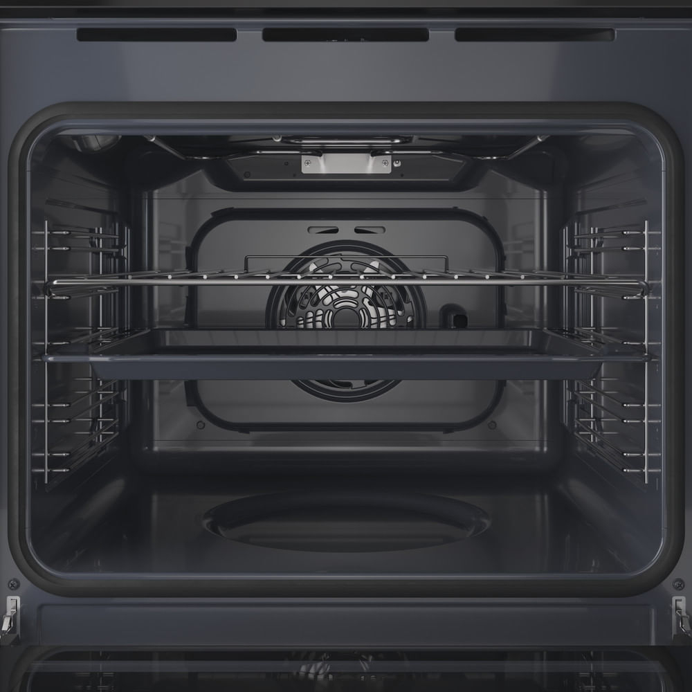Interno di forno vuoto e scuro con griglie e un vassoio. Una ventola è visibile sul retro. La porta del forno è aperta.