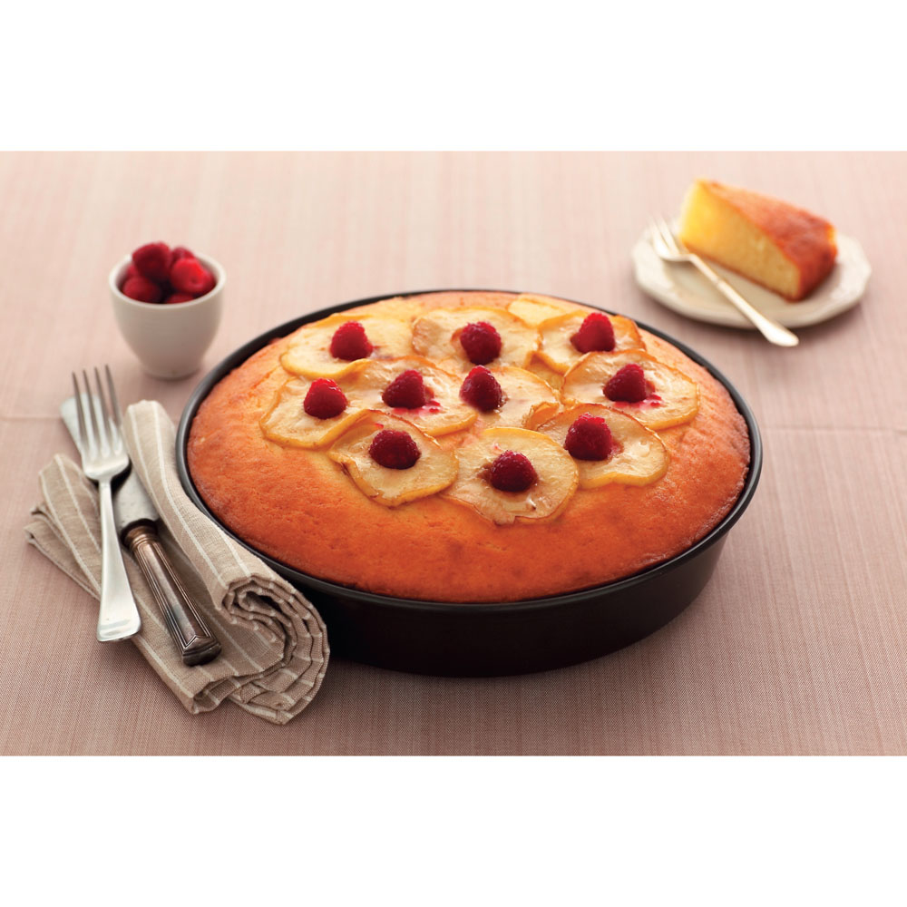 Torta con fette di pera e lamponi. Una fetta di torta su un piatto. Forchetta, coltello e una ciotola di lamponi.