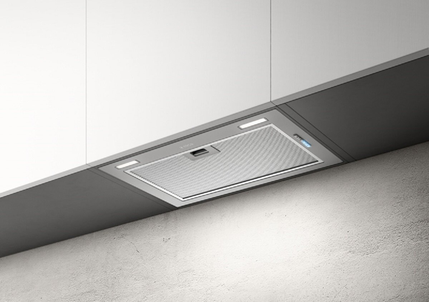 Una moderna cappa da cucina è installata sotto un armadio. È argentata e ha luci e un filtro a rete.