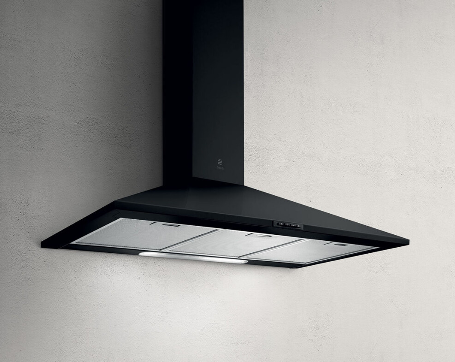 Una cappa nera è montata su un muro bianco strutturato. Ha un design inclinato con luce integrata e filtri metallici.